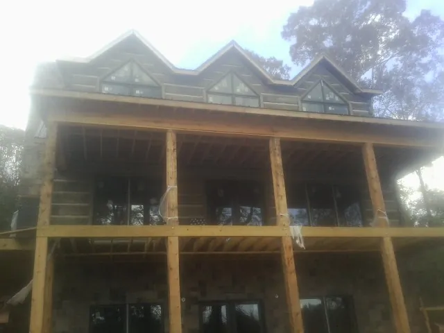 Dormers and porch framing on a large log home under construction — Roof Coating work by our crew in Juneau