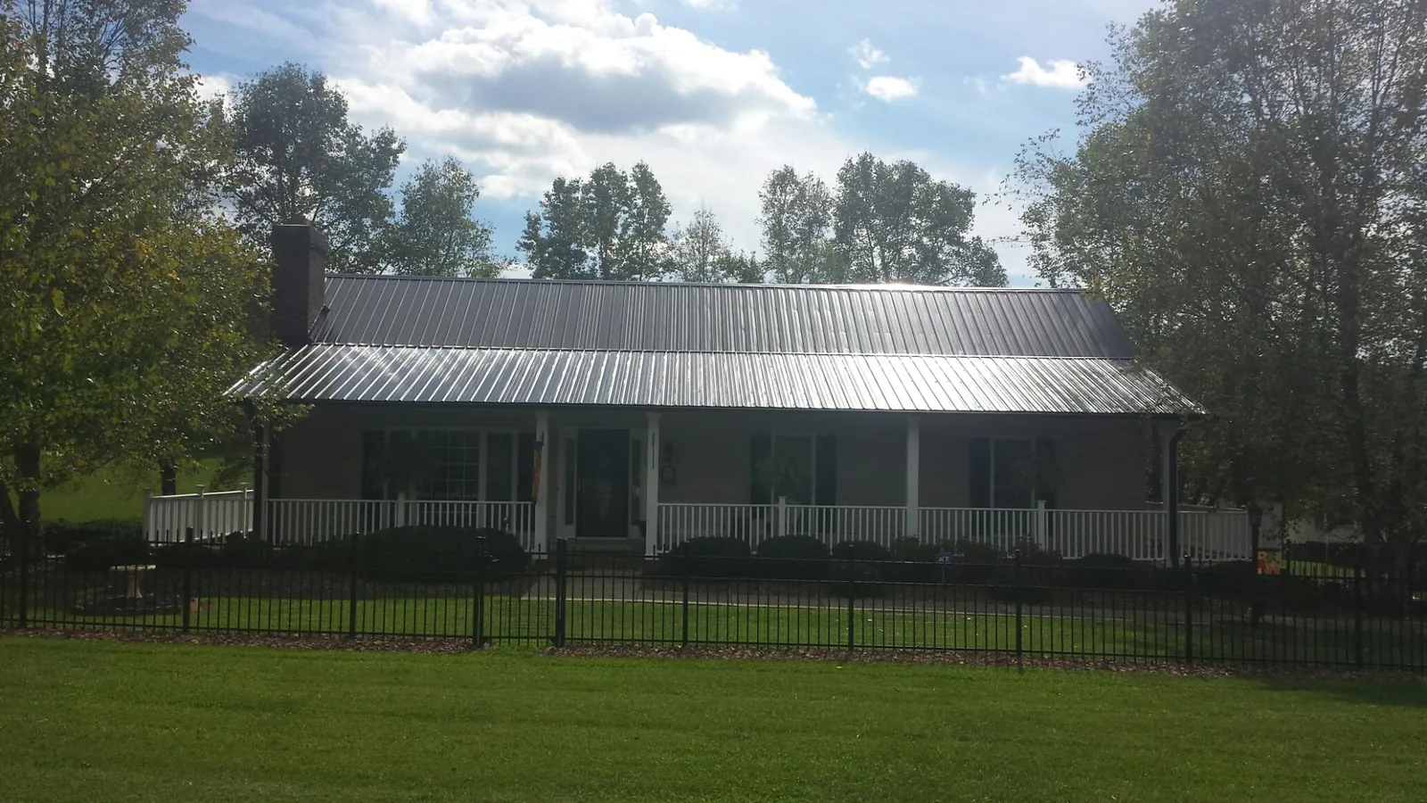 Gray metal roof on a brick ranch with a full width front porch — Gutter Guard Installation work by our crew in Juneau