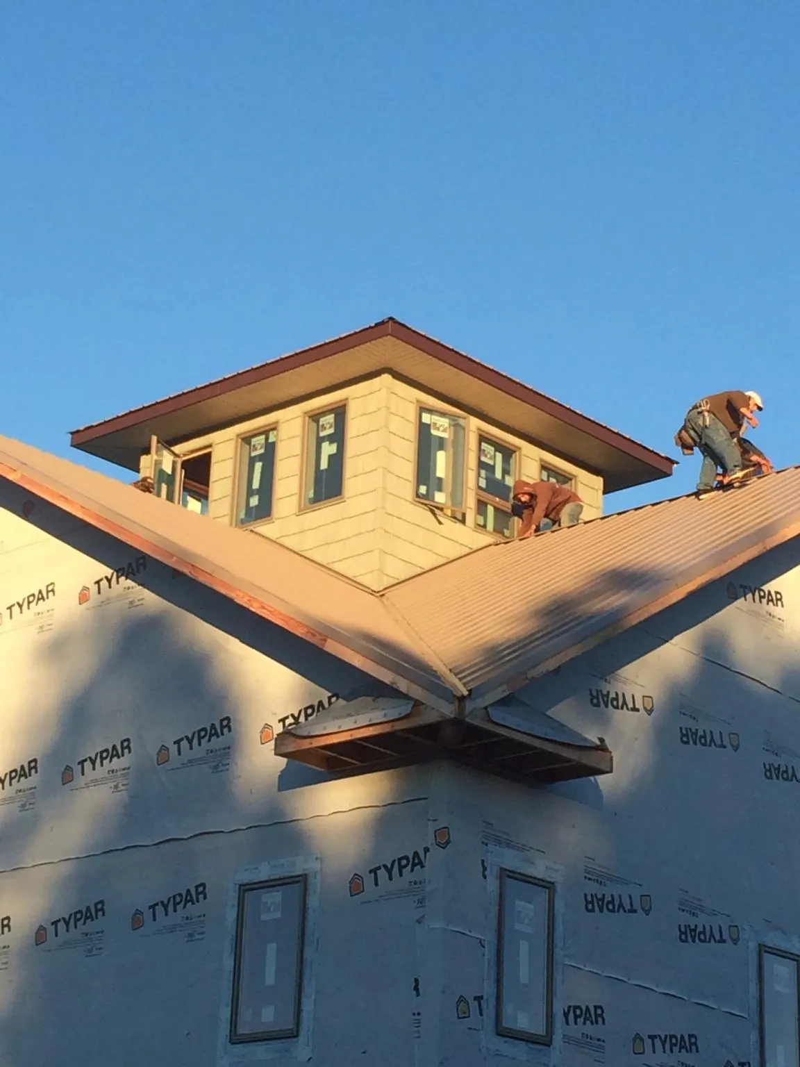 Roofers working around a rooftop cupola on a new metal roof at sunset — Roof Waterproofing in Juneau by Roofing Brothers